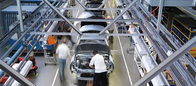 Ein Autofließband in einer Fabrik mit Arbeitern, die sich um die verschiedenen Phasen der Autoproduktion kümmern.