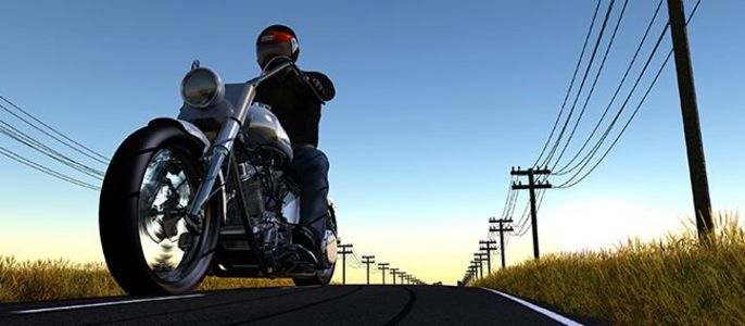 Ein Motorradfahrer fährt auf einer Straße mit Telefonmasten und Stromleitungen im Hintergrund, vor einem klaren Himmel bei Sonnenuntergang.