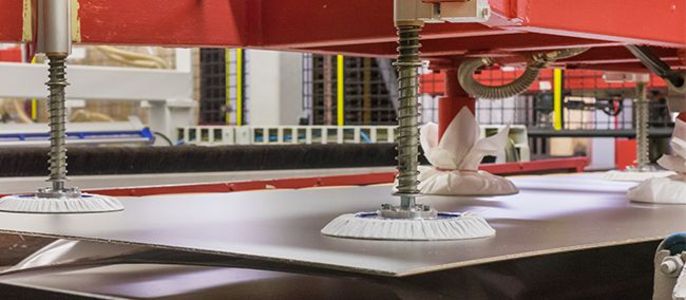 Eine Maschine mit roten und silbernen Teilen, die mit weißen Saugnäpfen ausgestattet ist und auf einer ebenen Fläche aufgestellt wird.