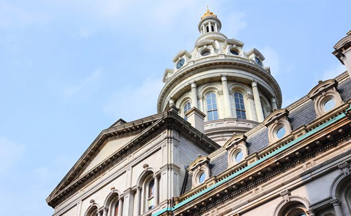 Ein großartiges architektonisches Bauwerk mit einer markanten Kuppel, kunstvollen Details und einer goldenen Turmspitze vor einem klaren blauen Himmel.