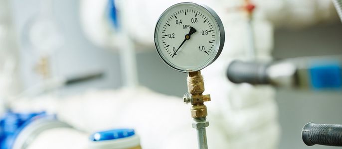 Ein Manometer, das an ein blau-weißes System angeschlossen ist, mit einem Messwert von 0,2.