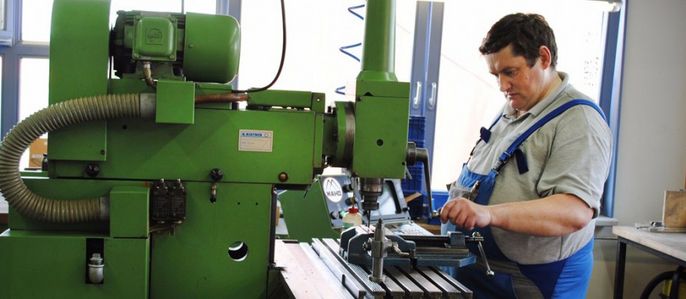 Ein Mann arbeitet an einer grünen Maschine in einer Werkstatt.