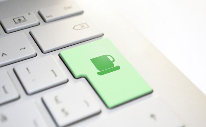 Eine Computertastatur mit einer grünen Taste, auf der das Symbol einer Tasse abgebildet ist.