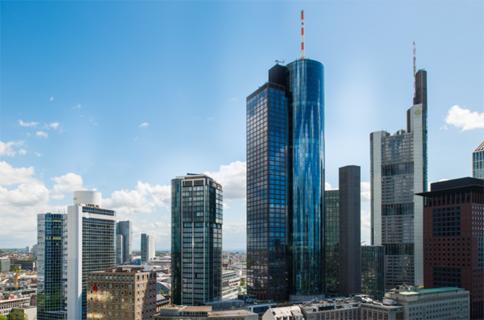 Eine Stadtsilhouette mit hohen, modernen Wolkenkratzern, einige mit spiegelnden Glasfassaden, vor einem klaren, blauen Himmel mit ein paar vereinzelten Wolken.