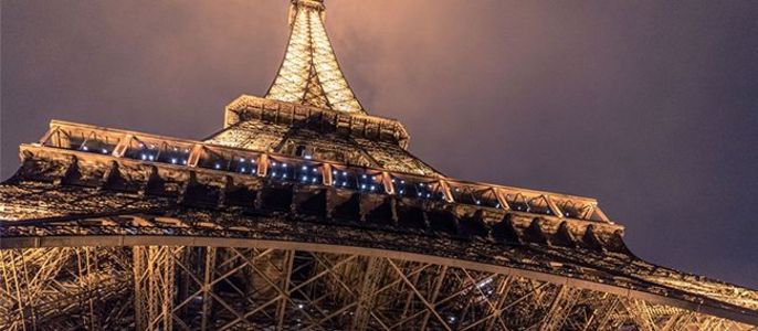 Der Eiffelturm beleuchtet vor einem dunklen Himmel.