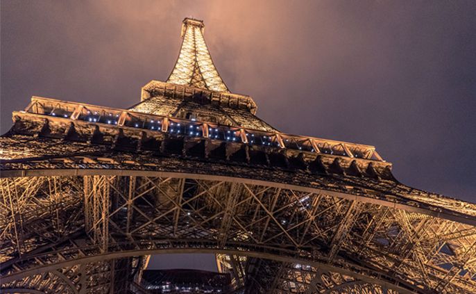 Der Eiffelturm beleuchtet vor einem dunklen Himmel.