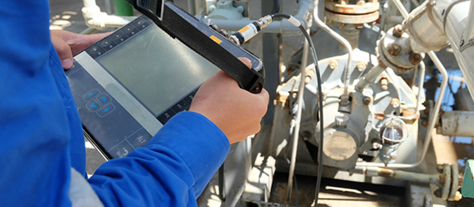 Eine Person in blauer Uniform benutzt ein Tablet zur Überprüfung von Maschinen.