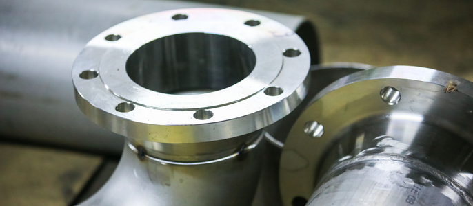 Metallteile, insbesondere Flansche und Rohre, wobei ein Flansch eine Bohrung und mehrere Schrauben aufweist.