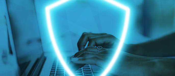 Eine Person tippt auf einem Laptop mit einem digitalen Schildsymbol über der Tastatur, das Cybersicherheit symbolisiert.