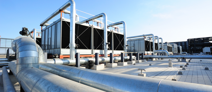 Eine große Industrieanlage mit mehreren Kühltürmen, großen Rohren und anderen Ausrüstungen, alles vor einem klaren blauen Himmel.