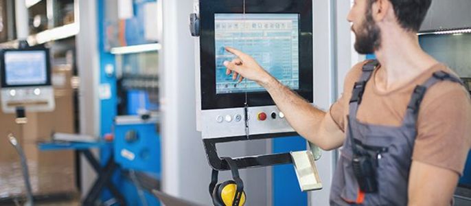 Ein Mann in einer Werkstatt, der auf einen Computerbildschirm zeigt, auf dem Daten angezeigt werden.