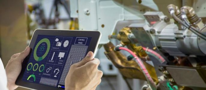 Eine Person hält ein Tablet in der Hand, auf dem verschiedene Daten zu Maschinen angezeigt werden, wobei der Schwerpunkt auf den CO2-Emissionen und den Energieverbrauchsdaten liegt.