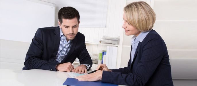 Zwei Fachleute, ein Mann und eine Frau, diskutieren an einem Tisch.