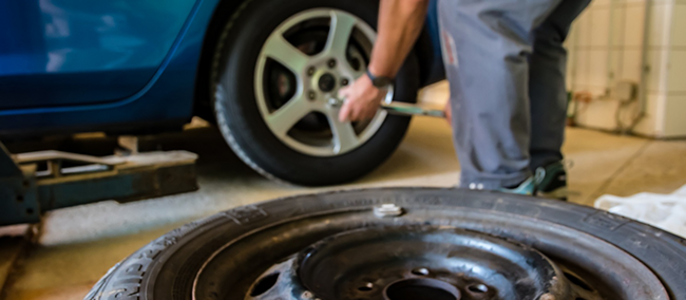 Eine Person, die in einer Werkstatt an einem Autoreifen arbeitet.