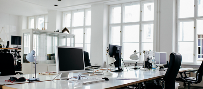 Eine moderne Büroumgebung mit mehreren Computern, einem weißen Schreibtisch und schwarzen Stühlen.