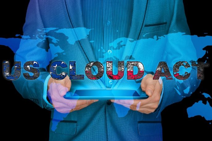 Ein Mann im Anzug hält ein Tablet in der Hand, auf dem die Worte "US CLOUD ACT" vor dem Hintergrund einer Weltkarte zu lesen sind.