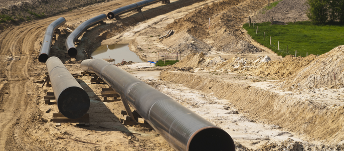 Eine weitläufige Landschaft mit mehreren großen Rohren, die auf dem Boden ausgelegt sind, bereit für den Bau.