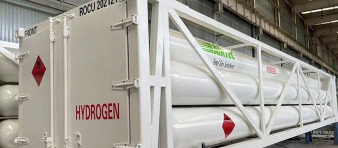Ein weißer Container mit der Aufschrift "HYDROGEN" und einem Warnschild, der zylindrische Tanks enthält, in einer Lagerhalle.
